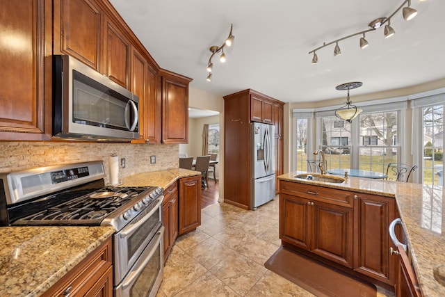 kitchen featuring stainless steel appliances, a sink, light stone counters, and decorative backsplash