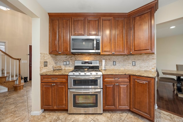 kitchen featuring tasteful backsplash, appliances with stainless steel finishes, brown cabinets, and light stone counters