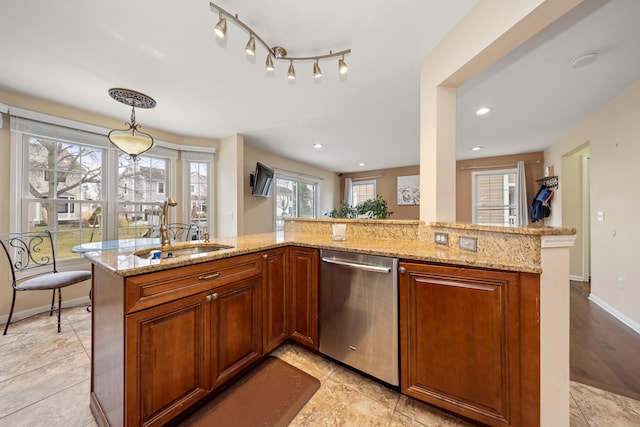 kitchen with decorative light fixtures, stainless steel dishwasher, brown cabinetry, a sink, and light stone countertops