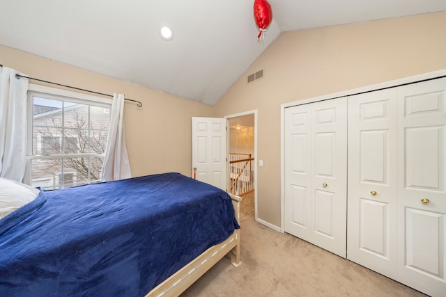 bedroom featuring a closet, visible vents, vaulted ceiling, and light carpet