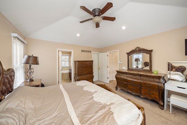 bedroom with light carpet, visible vents, a ceiling fan, ensuite bathroom, and vaulted ceiling