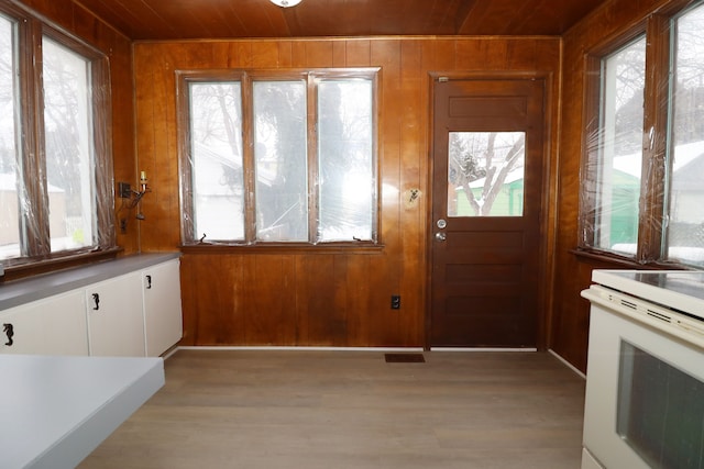 interior space featuring light wood-type flooring, wood ceiling, and wooden walls