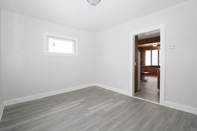 spare room with baseboards and wood finished floors