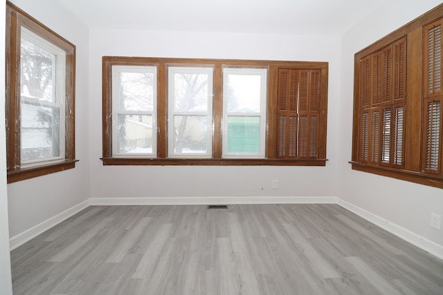 unfurnished room with light wood-style flooring, visible vents, and baseboards