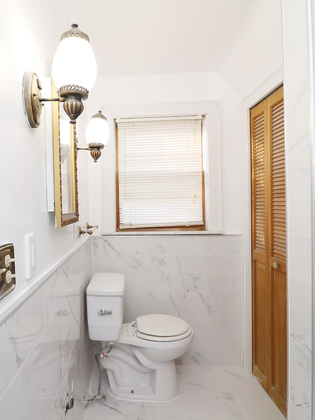 bathroom featuring a wainscoted wall, marble finish floor, a closet, and toilet