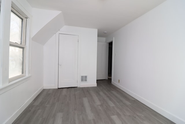 bonus room featuring baseboards, visible vents, vaulted ceiling, and light wood finished floors