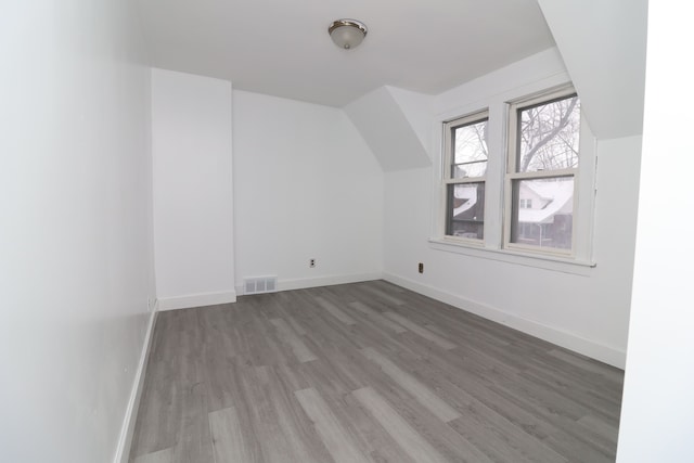 additional living space featuring visible vents, vaulted ceiling, baseboards, and wood finished floors