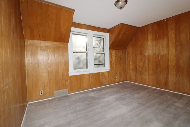 bonus room featuring wood walls, baseboards, visible vents, and wood finished floors