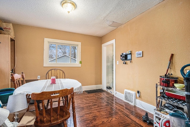 dining space featuring a textured ceiling, wood finished floors, visible vents, and baseboards