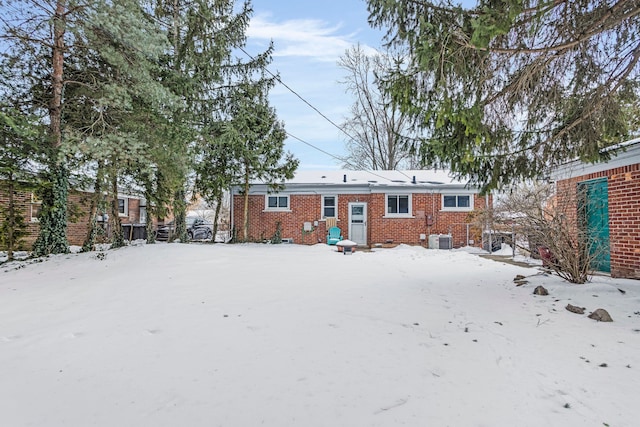 snow covered property featuring central AC and brick siding