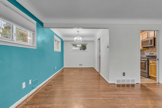 unfurnished dining area with light wood finished floors, visible vents, and a chandelier