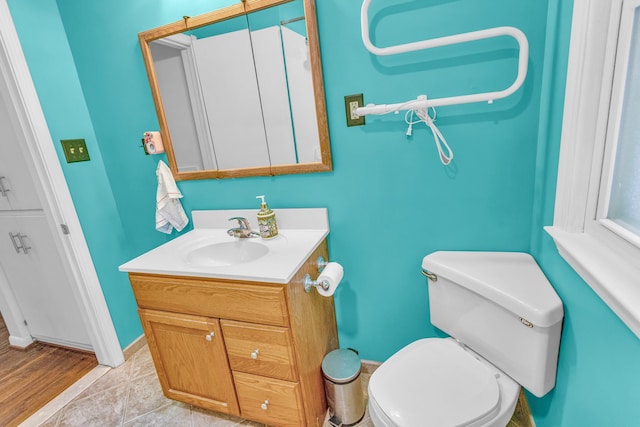 half bath with baseboards, vanity, toilet, and tile patterned floors