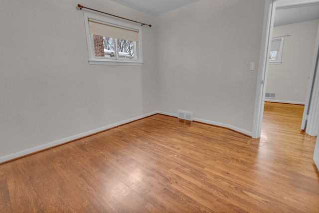 empty room featuring light wood-style flooring, visible vents, and baseboards