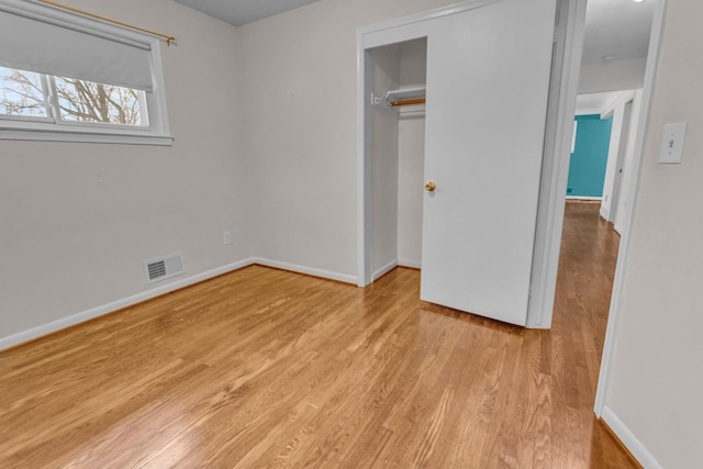 unfurnished bedroom with light wood-style flooring, a closet, visible vents, and baseboards