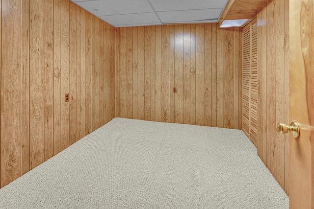 carpeted spare room with a drop ceiling and wooden walls