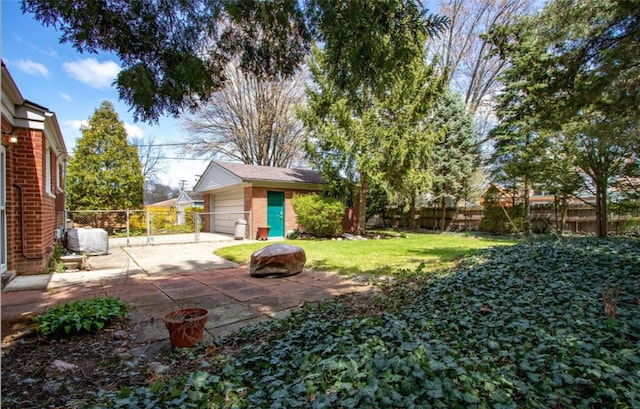 view of yard with a fenced backyard, a detached garage, a patio, and an outdoor structure