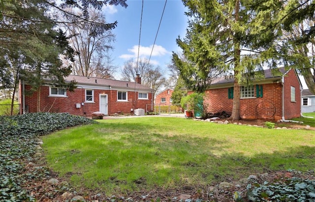 exterior space featuring a yard, brick siding, a chimney, and fence