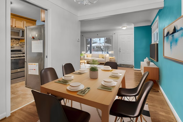 dining space with light wood-style flooring and baseboards