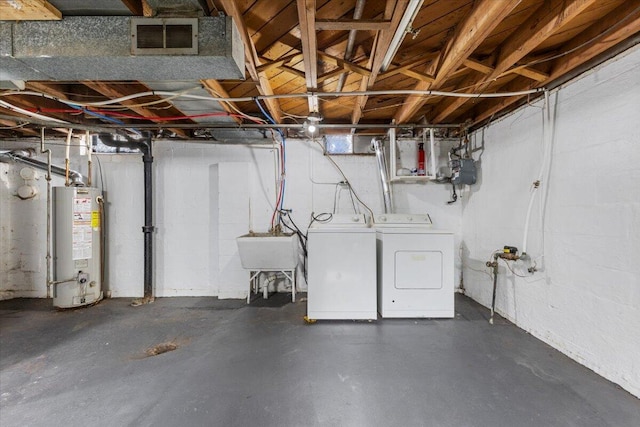 unfinished below grade area with a sink, washing machine and dryer, visible vents, and gas water heater