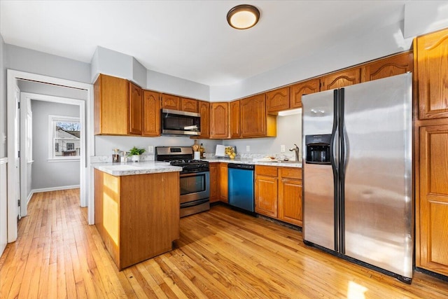 kitchen featuring a sink, stainless steel appliances, brown cabinetry, and light countertops