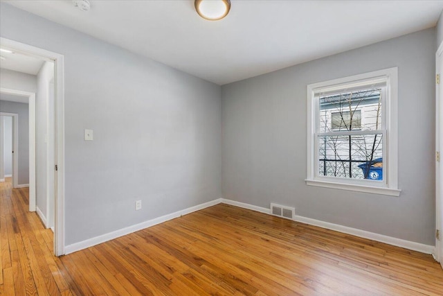 empty room featuring light wood-type flooring, visible vents, and baseboards