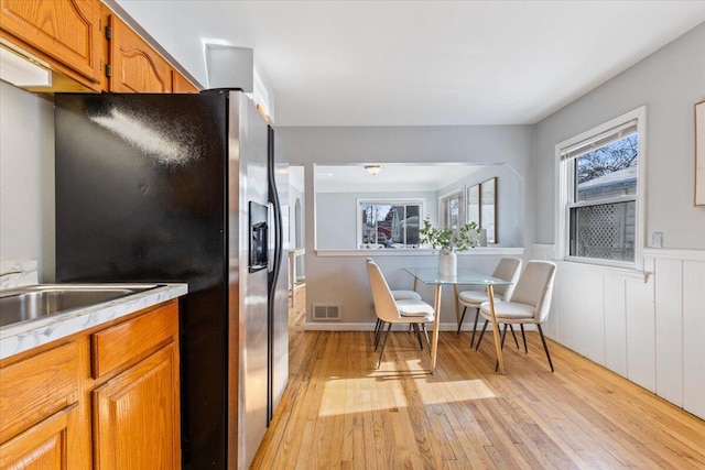 kitchen featuring brown cabinetry, light countertops, visible vents, and stainless steel fridge with ice dispenser