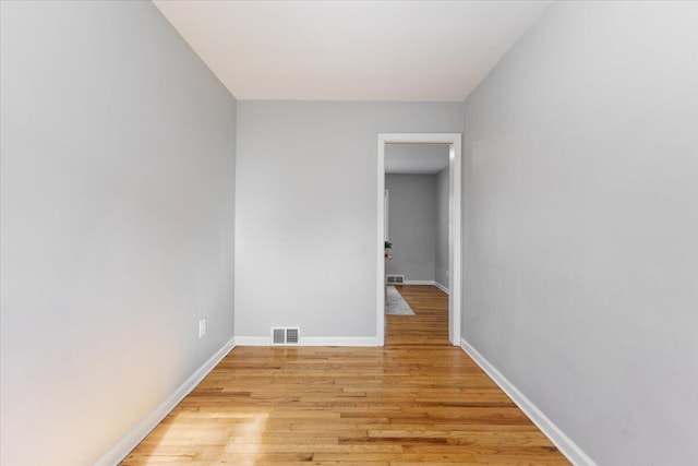 empty room featuring light wood finished floors, visible vents, and baseboards