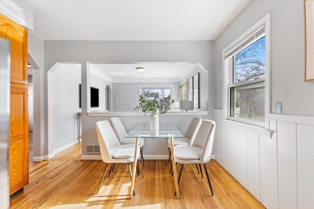 dining room with a healthy amount of sunlight, light wood-style floors, and a wainscoted wall