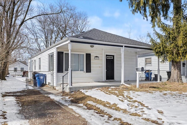 view of front of house featuring covered porch, fence, and roof with shingles