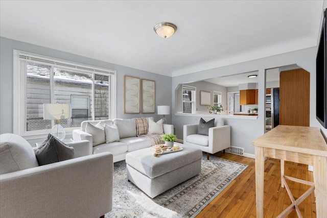 living room with light wood-style floors, baseboards, and visible vents