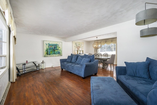 living area featuring a baseboard heating unit, a chandelier, and dark wood-style flooring