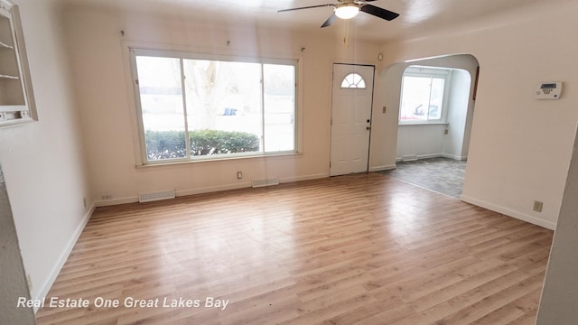 unfurnished room featuring a wealth of natural light, visible vents, and arched walkways