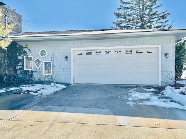 snow covered garage featuring driveway