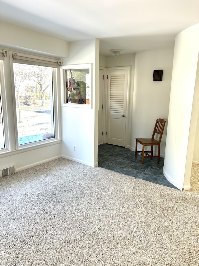 unfurnished room featuring dark colored carpet, visible vents, and baseboards