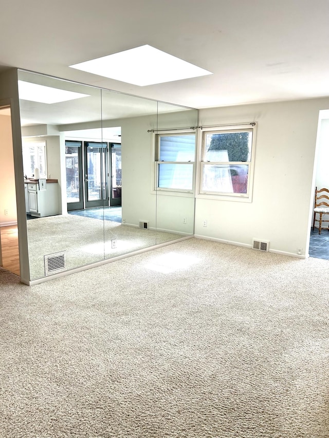 spare room with carpet, visible vents, and baseboards