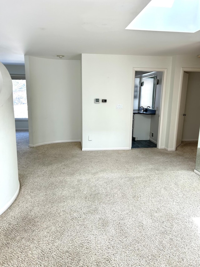 spare room featuring carpet, baseboards, and a skylight