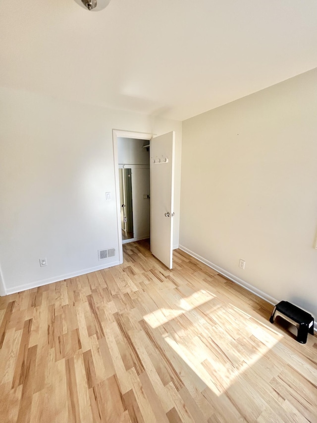 unfurnished bedroom with light wood-type flooring, visible vents, and baseboards