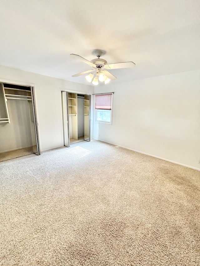 unfurnished bedroom with multiple closets, carpet, baseboards, and a ceiling fan