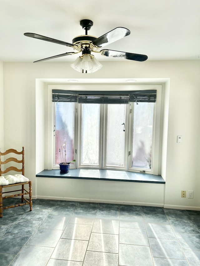 unfurnished room featuring a ceiling fan and baseboards