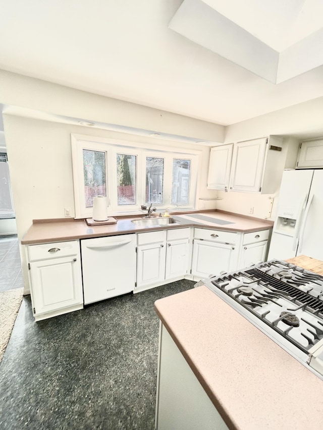 kitchen with white appliances, a sink, and white cabinets