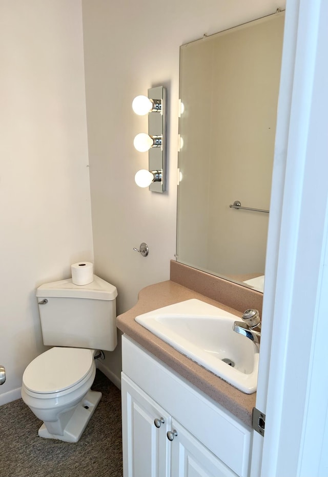 bathroom featuring toilet, vanity, and baseboards