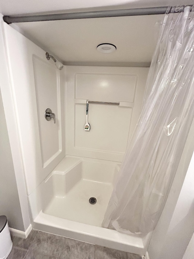 bathroom with a stall shower, baseboards, and tile patterned floors