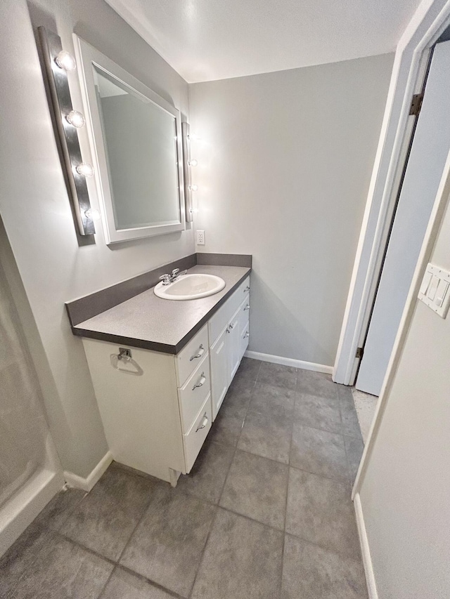 bathroom featuring tile patterned flooring, baseboards, and vanity