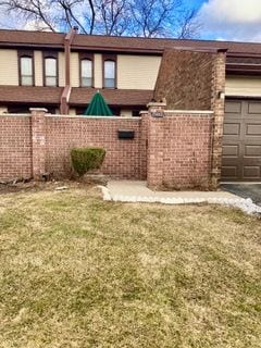 back of property featuring an attached garage, fence, brick siding, and driveway