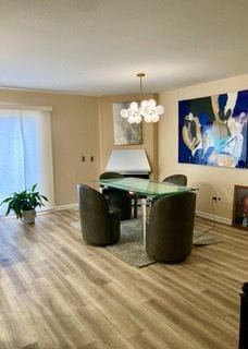 unfurnished dining area with an inviting chandelier, baseboards, and wood finished floors