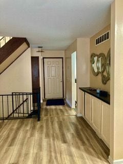 corridor featuring an upstairs landing, wood finished floors, and visible vents