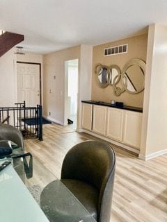 living room with visible vents, baseboards, and light wood-style floors