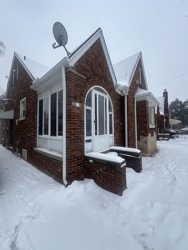 view of snow covered exterior featuring brick siding