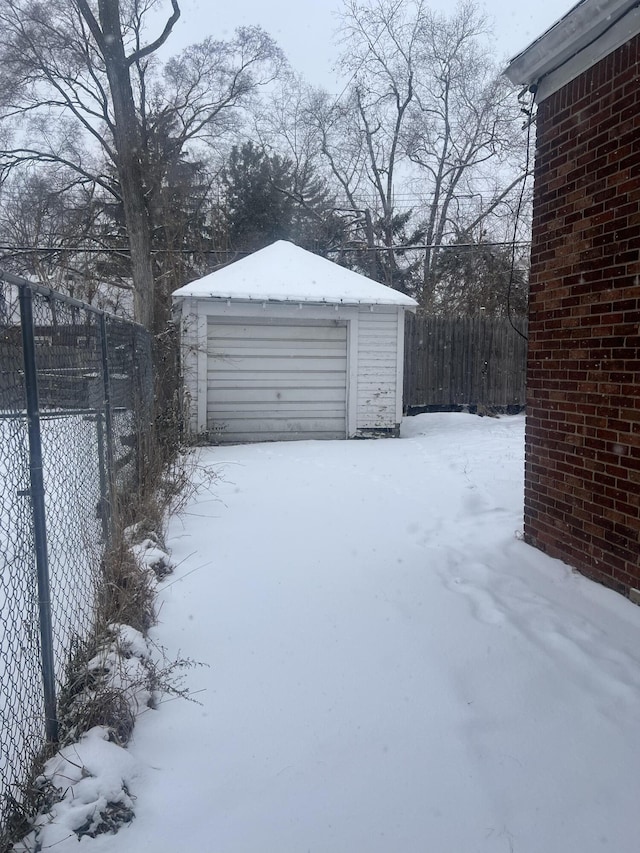 snow covered garage with a detached garage and fence