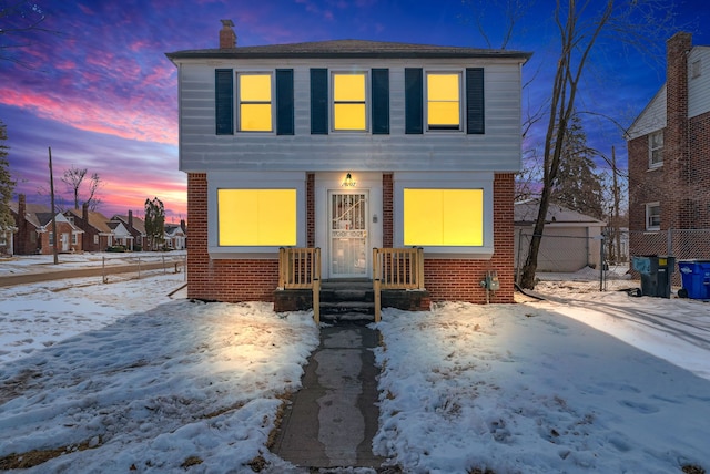 view of front of home featuring a chimney, a detached garage, fence, and brick siding